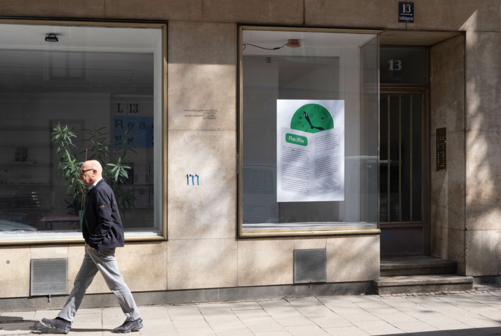 Ein Herr schreitet an einer Ladenzeile vorbei, im Fenster hängt ein Plakatr mit der Aufschrift "Re:Re" und einer grünen Uhr.