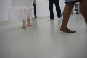 Foto von Füßen vierer Menschen, die barfuß ode rin Socken im Raum herumlaufen.