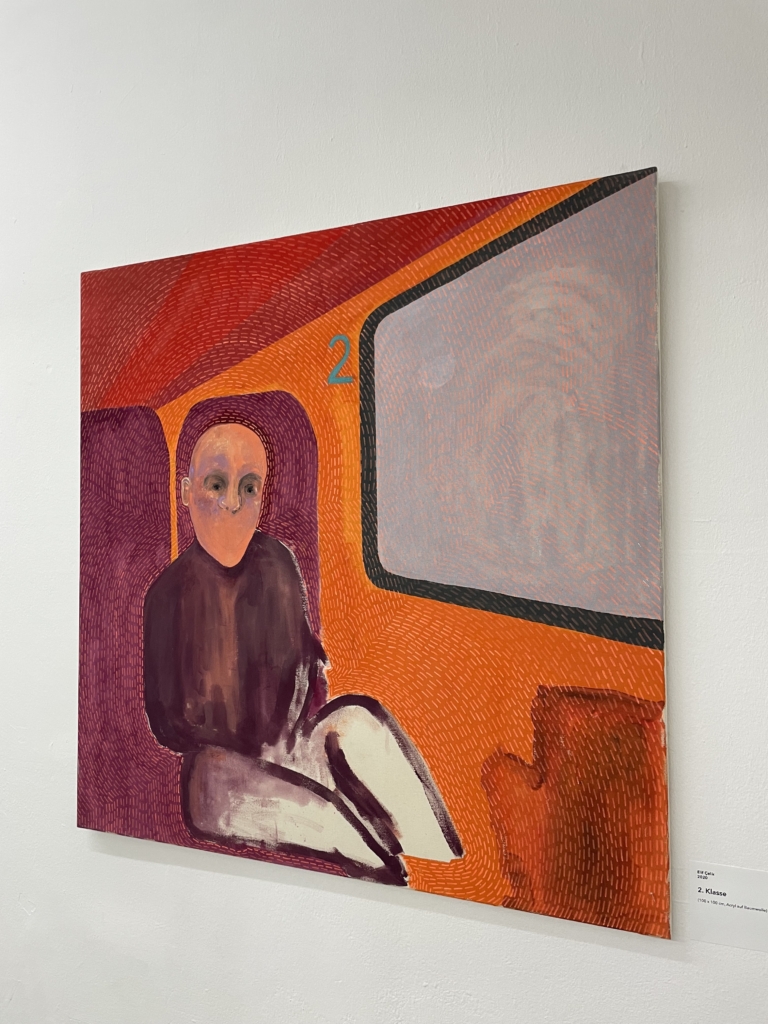 Ein abstraktes, orange-rotes Gemälde an der Wand zeigt eine Figur, die in einem Zugabteil sitzt, links neben dem Zugfenster die Zahl 2.